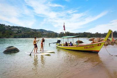 Guests on a paddle board next to a long boat