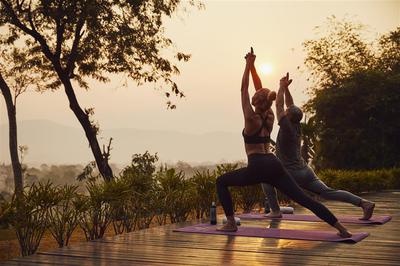 Couple taking sunrise yoga class at garden terrace